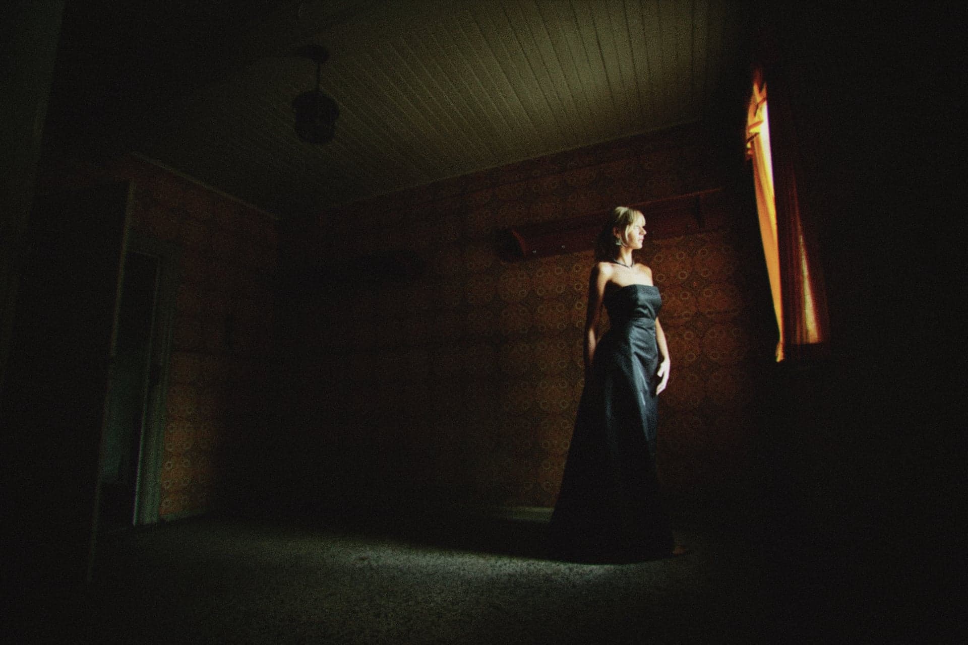 A woman in a long dress standing in a dim room