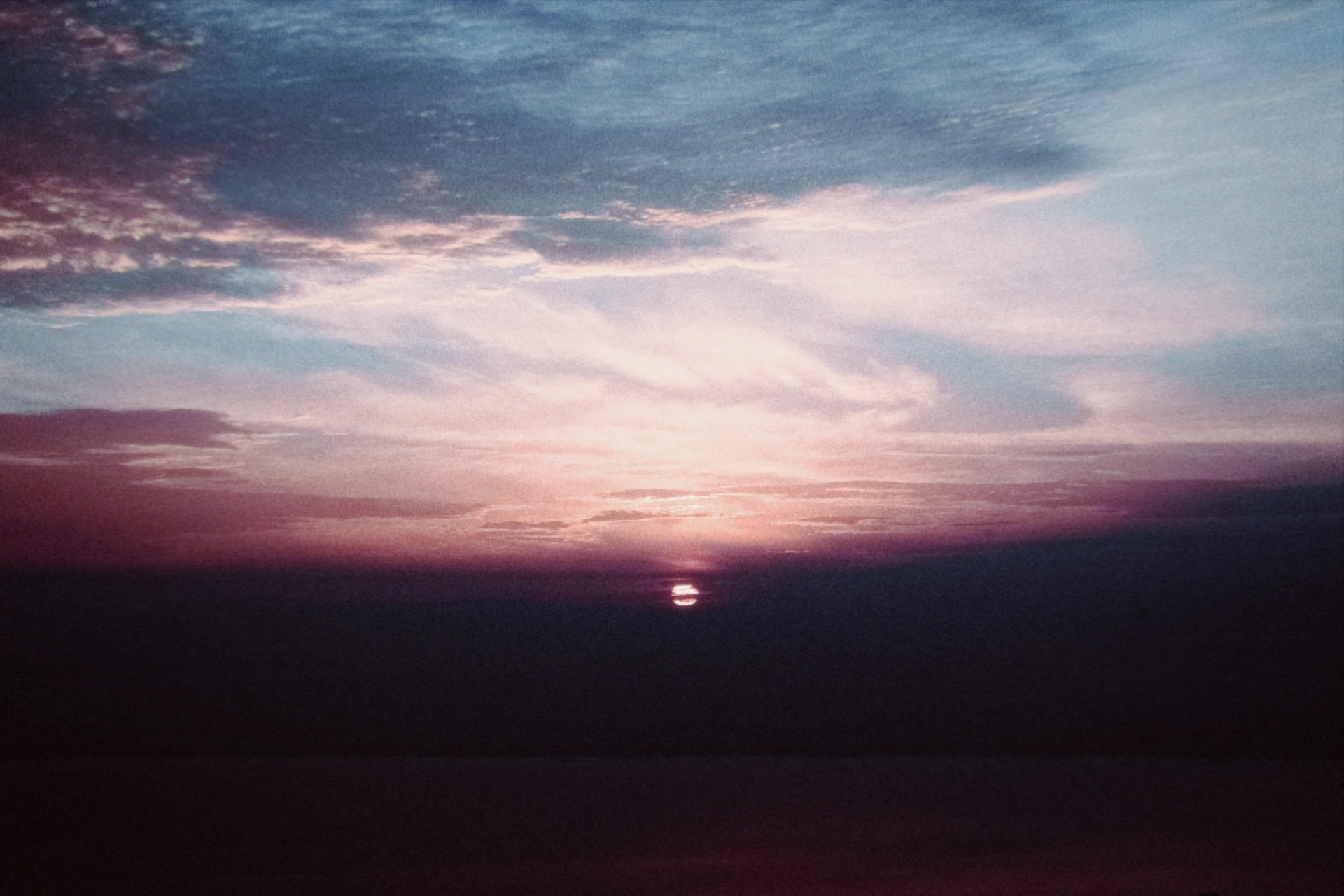 The sun setting over the sea under pink and blue clouds, rendered with the Nostalgia preset
