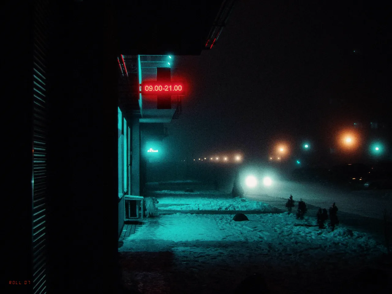 A dark street corner on a snowy night, lit teal, with a red opening-hours sign and distant headlights, artifact ID on
