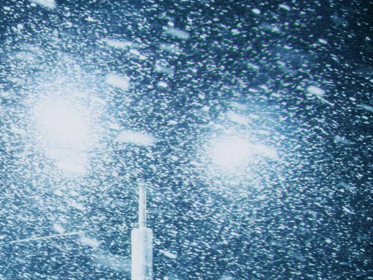 Two street lamps glowing through heavy falling snow at night, with chromatic aberration at 50%, shown at 100%