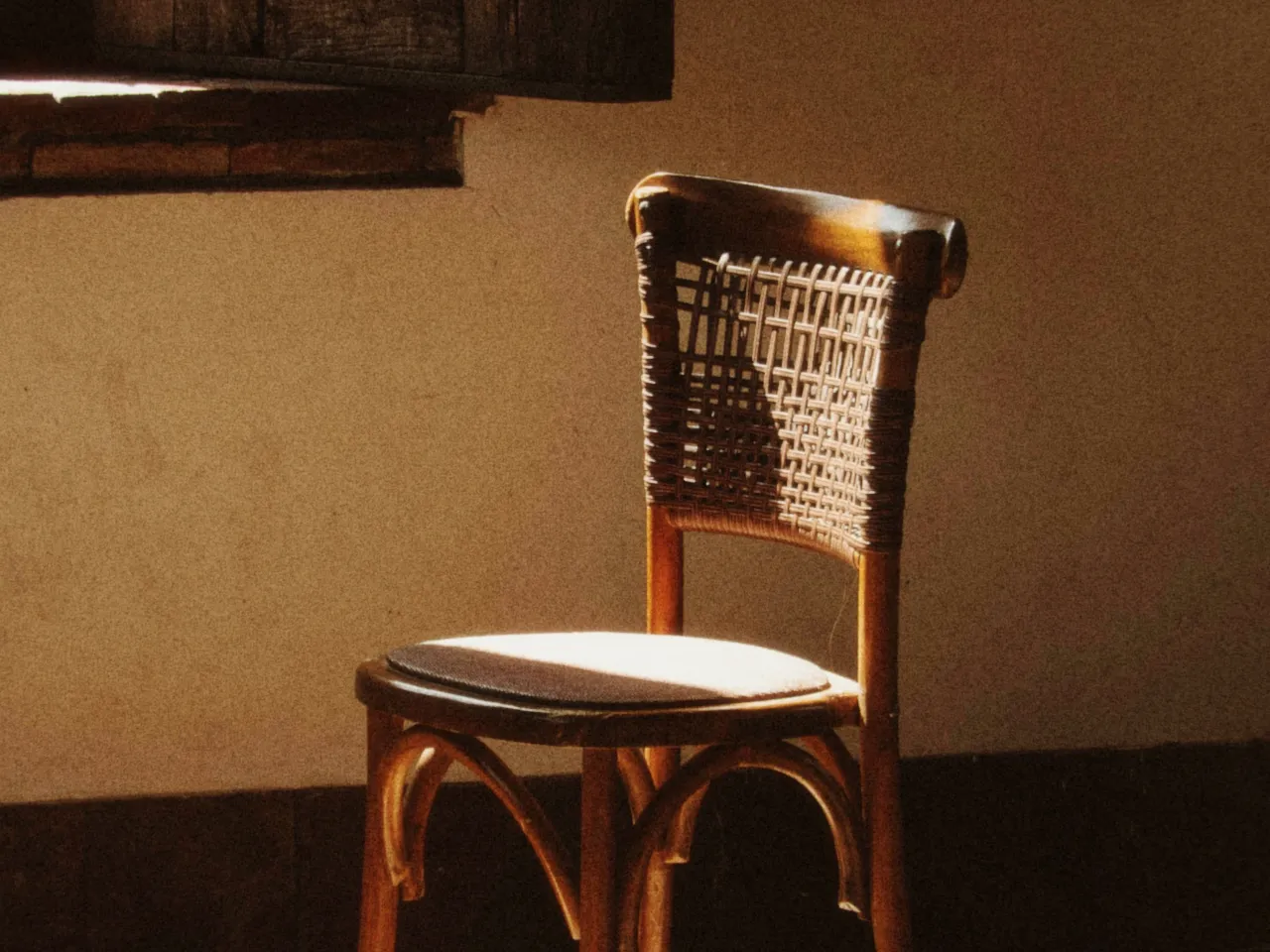 An empty wooden chair in a dim room, lit by a single window, with film speed at 800 ASA, shown at 100%