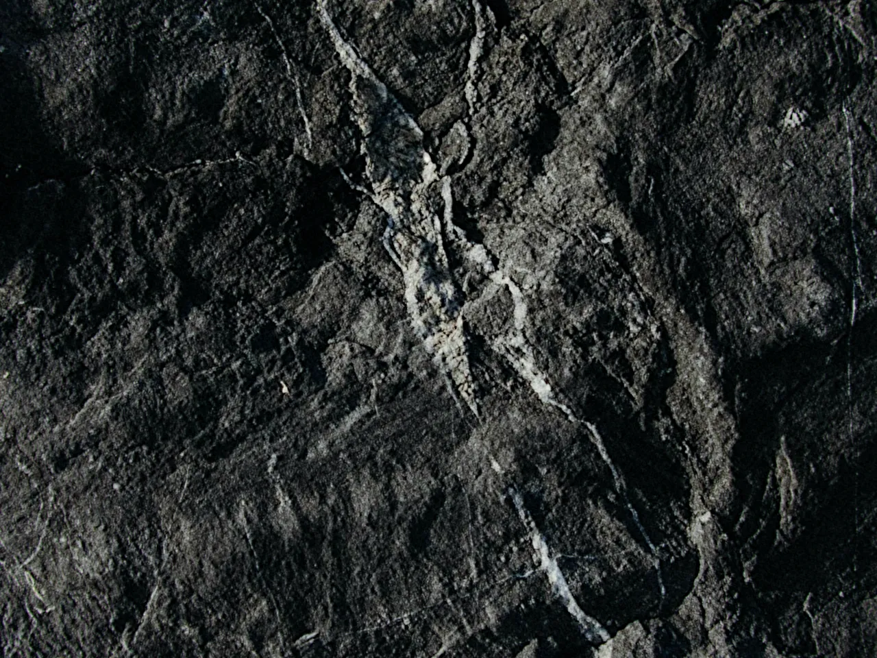 Rough dark stone, every ridge and crack of its surface in relief, with texture at 50%, shown at 100%