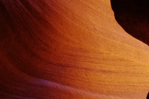 Density at +20 deepens the canyon’s orange, a close crop of the curving orange sandstone walls of a slot canyon